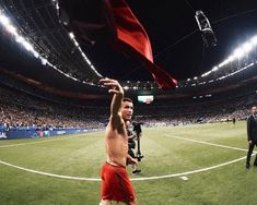 a man in red shorts holding up a red flag at a soccer game with other people watching