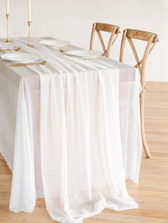 the table is set with white linens and place settings for two people to sit at