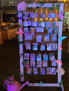 an outdoor photo display with pictures and flowers on it's easel at night