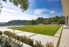 a large yard with grass and trees next to a swimming pool in the middle of it