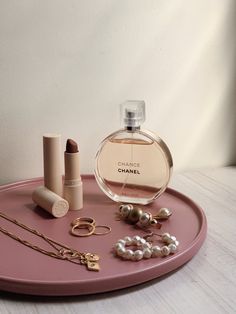 a pink tray topped with jewelry and a bottle of chanel eau de parfuit