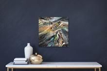 an abstract painting hangs on the wall above a console table with a vase and books