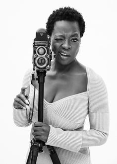 a black and white photo of a woman holding a camera