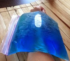 a person's arm with a blue bag on top of it that is sitting on a wooden floor