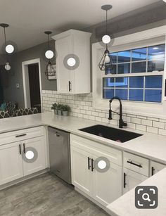 a kitchen with white cabinets and gray tile flooring is pictured in this image, there are lights hanging from the ceiling over the sink