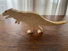 a wooden toy dinosaur on a table with curtains in the background