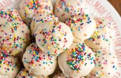 a white plate topped with frosted donuts covered in sprinkles on top of a wooden table