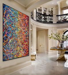 a large painting hanging on the wall in a living room next to a spiral staircase