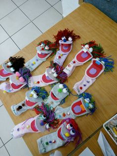 several pairs of shoes made out of paper machs on a wooden table with white tile flooring