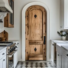 a kitchen with an arched wooden door and black and white checkered flooring is shown