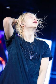 a woman with her hair blowing in the wind while standing on stage at a concert