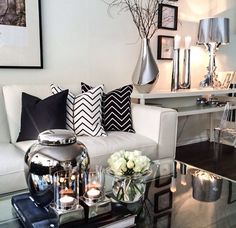 a living room filled with white furniture and lots of pillows on top of it's glass coffee table