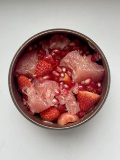 a bowl filled with fruit sitting on top of a white table next to a knife