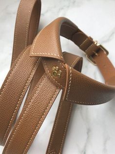 a pair of brown leather straps on a marble surface