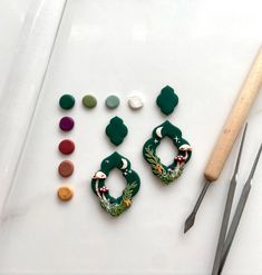 two pairs of earrings sitting on top of a table next to scissors and other crafting supplies