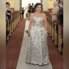 a woman in a silver dress is walking down the aisle with other people behind her