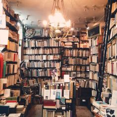 a room filled with lots of books next to a chandelier