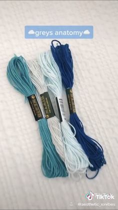 three skeins of blue and white yarn on top of a bed with the words greys anatomy above them