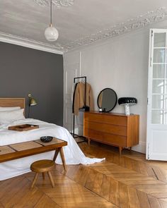 a bed room with a neatly made bed and a dresser next to the bed in it