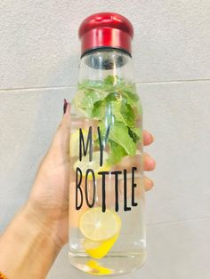 someone holding up a bottle with some lemons and mint in it that says, my bottle