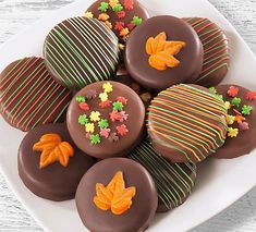 chocolate covered cookies decorated with autumn leaves on a white plate