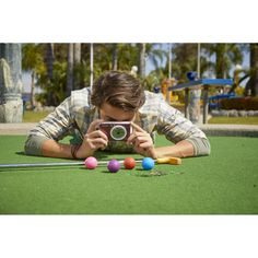 a man laying on the ground taking a photo with his camera and balls in front of him