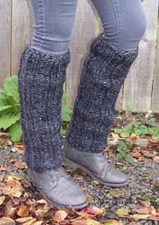 the legs of a woman wearing gray boots and leg warmers, standing in front of a fence