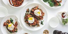 an overhead view of several plates of food with eggs on top and beans in the middle