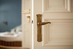 an open door with a handle on it in front of a white bed and blue wall