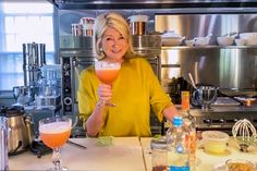 a woman holding up a drink in front of a counter