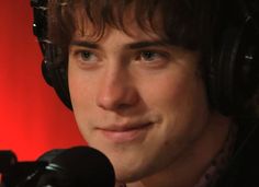 a young man wearing headphones and looking at the camera with a microphone in front of him