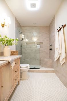 a white toilet sitting next to a walk in shower under a light fixture on a wall