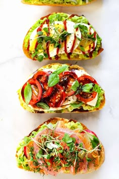 three open faced sandwiches with tomatoes, lettuce and other toppings on them