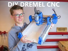 a man is holding a large piece of wood with a machine attached to it and the words diy dremel cnc above him