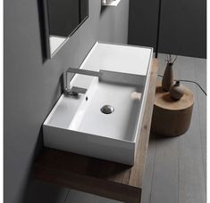 a white sink sitting on top of a wooden counter next to a mirror and vase