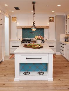 a large kitchen with white cabinets and blue backsplashing on the island counter