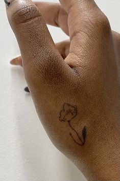 a hand with a flower tattoo on it's left thumb and the middle finger