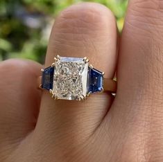 a woman's hand holding an engagement ring with two blue sapphires on it