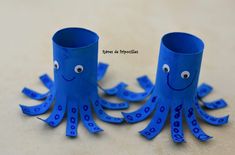 an octopus made out of toilet paper sitting on top of a table next to a cup