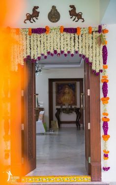 an entrance to a home decorated with flowers and garlands on the front door frame