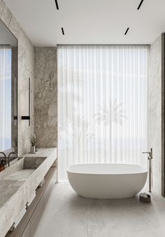 a large white bath tub sitting in a bathroom next to two sinks and a window