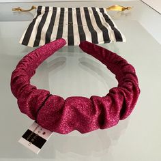 a pink and black hair tie sitting on top of a glass table next to a striped bag