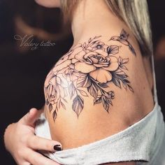 a woman with a flower tattoo on her shoulder and chest is looking at the camera