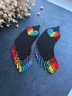 a pair of multicolored beaded earrings sitting on top of a blue surface