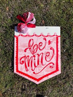 a red and white sign with the word be mine on it in front of someone's feet