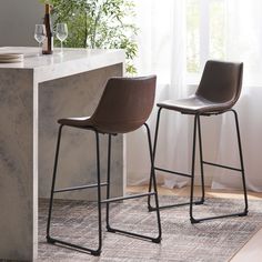 two brown chairs sitting on top of a rug next to a counter with wine glasses