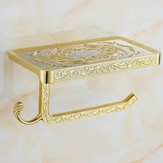 a gold metal shelf with a decorative design on the top and bottom, sitting on a marble surface