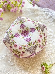 a close up of a small object on a doily with flowers in the background