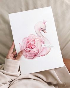 a person holding up a card with a pink flower in front of them and a swan on it