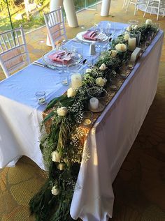 the table is set with candles, flowers and greenery for an elegant wedding reception